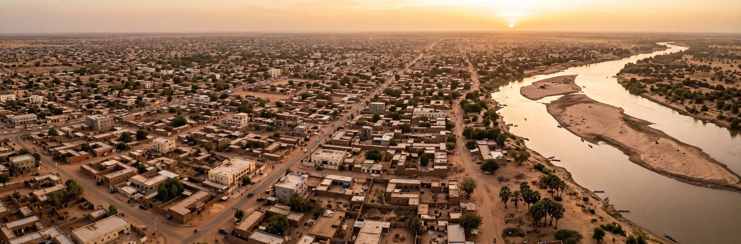 منظر جوي توضيحي لمدينة ساحلية على نهر عند الغروب